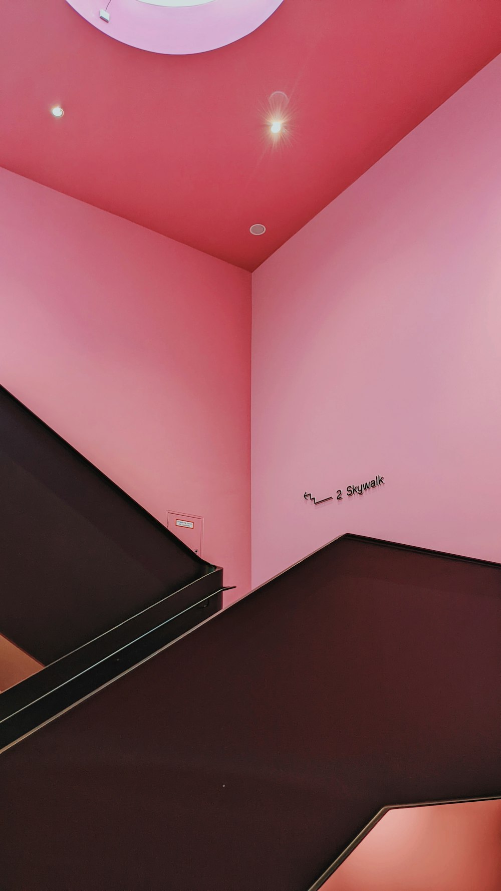 a pink room with stairs and a circular light