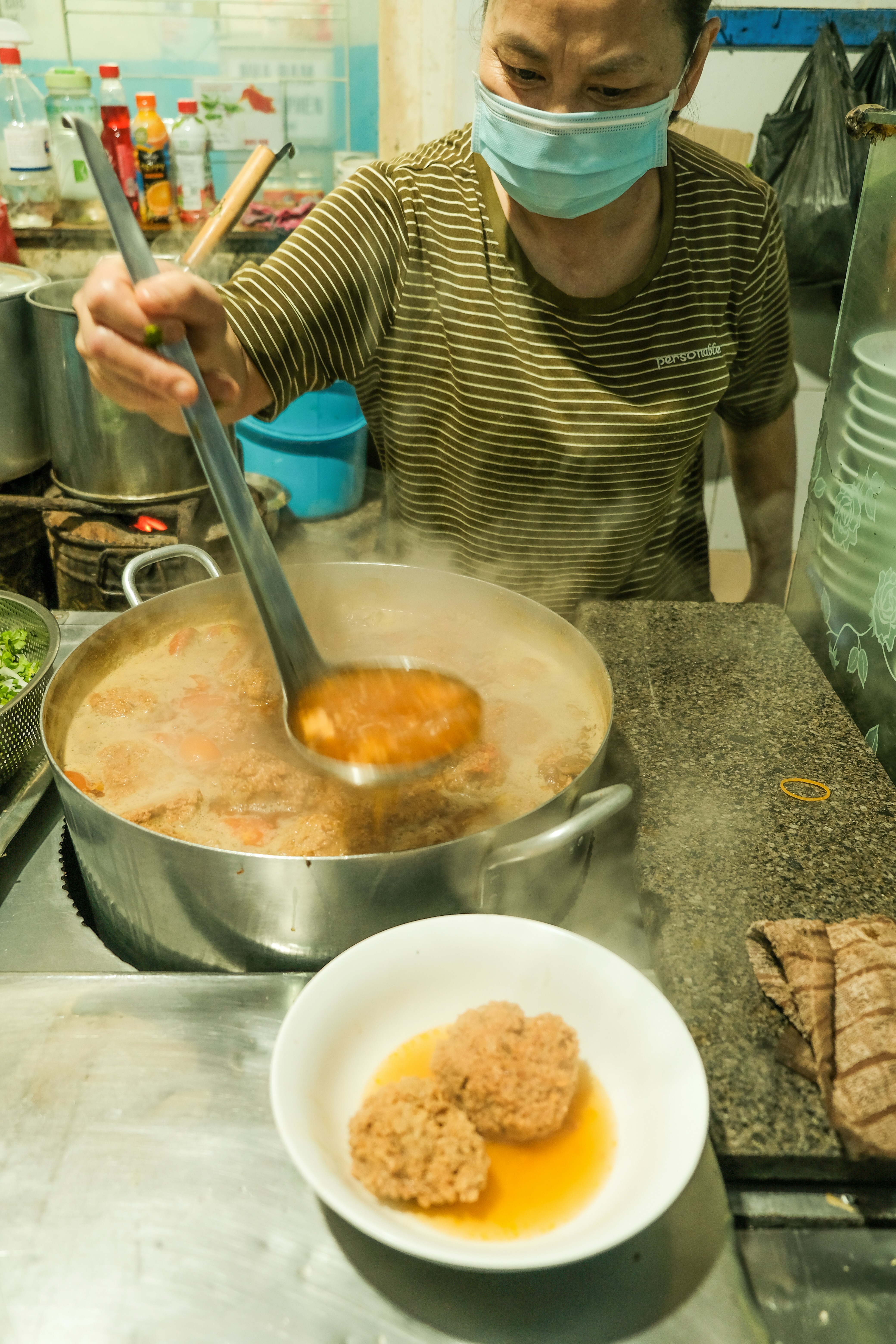 a woman in a mask stirring food in a pot