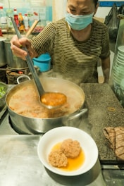 a woman in a mask stirring food in a pot