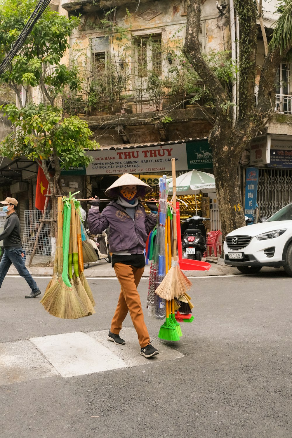 a woman walking across a street holding brooms