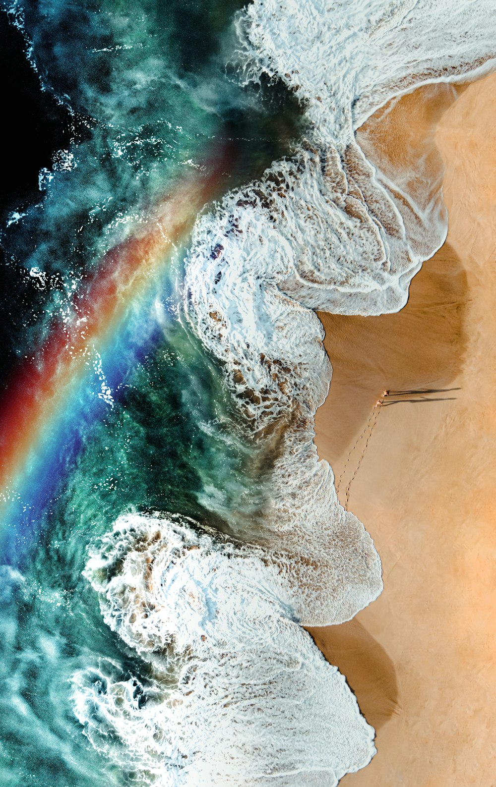 an aerial view of a rainbow in the ocean