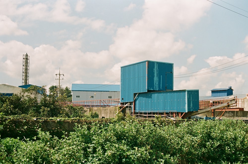 a large blue building sitting in the middle of a lush green field