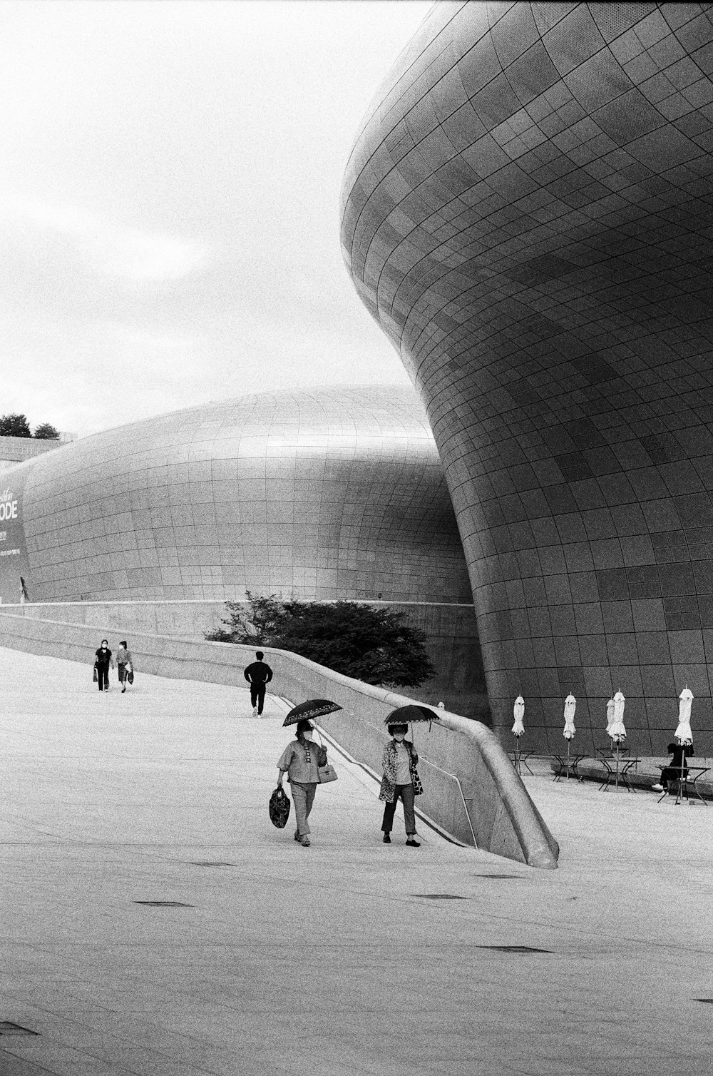 a black and white photo of people with umbrellas