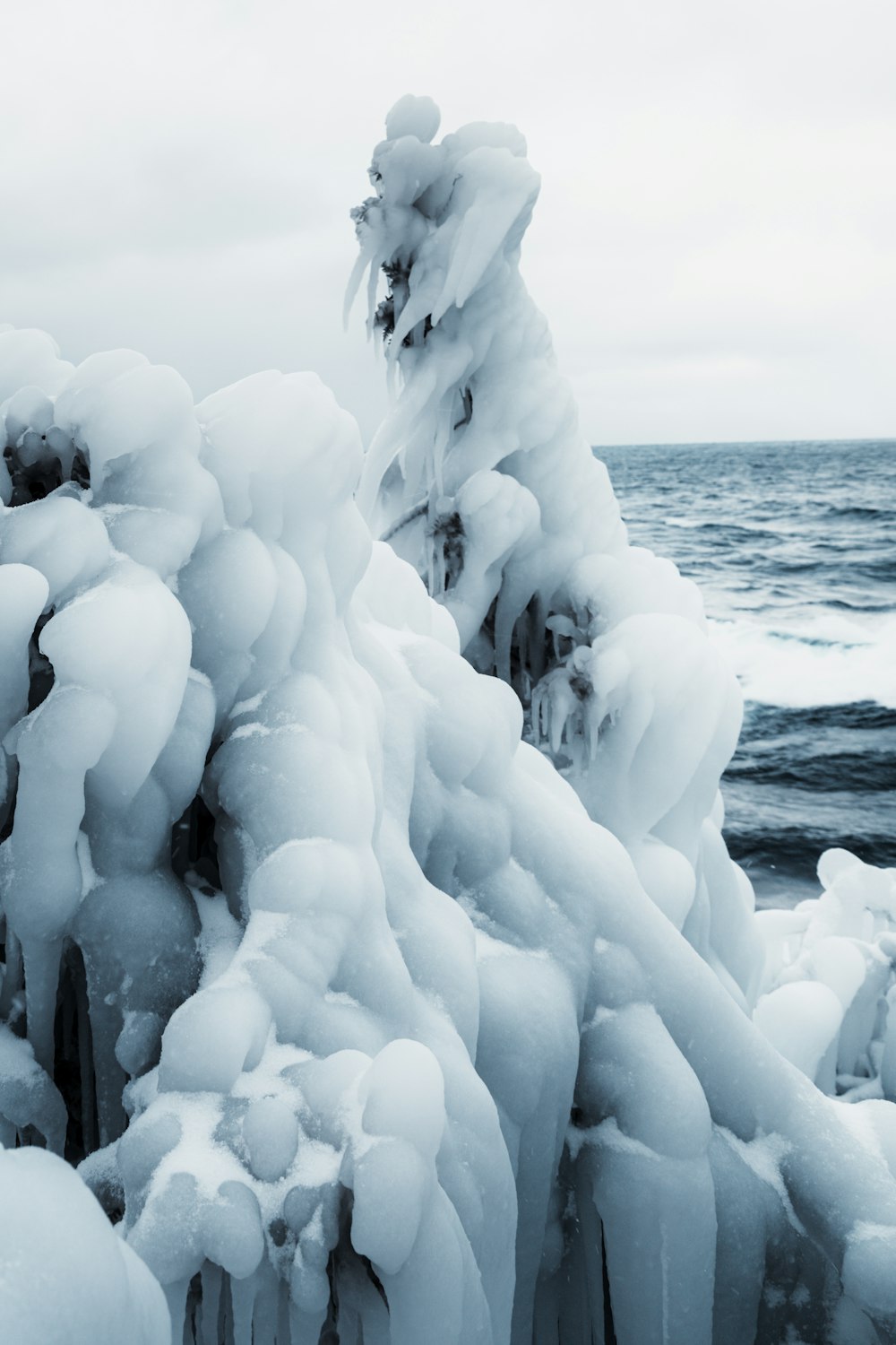 a bunch of ice covered rocks by the water