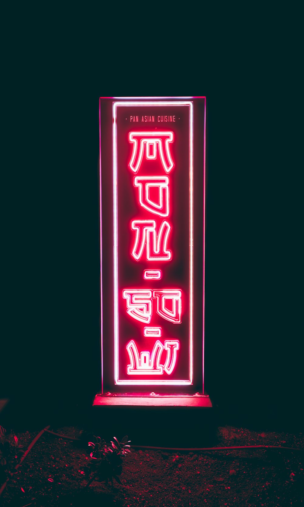 a red neon sign with asian writing on it