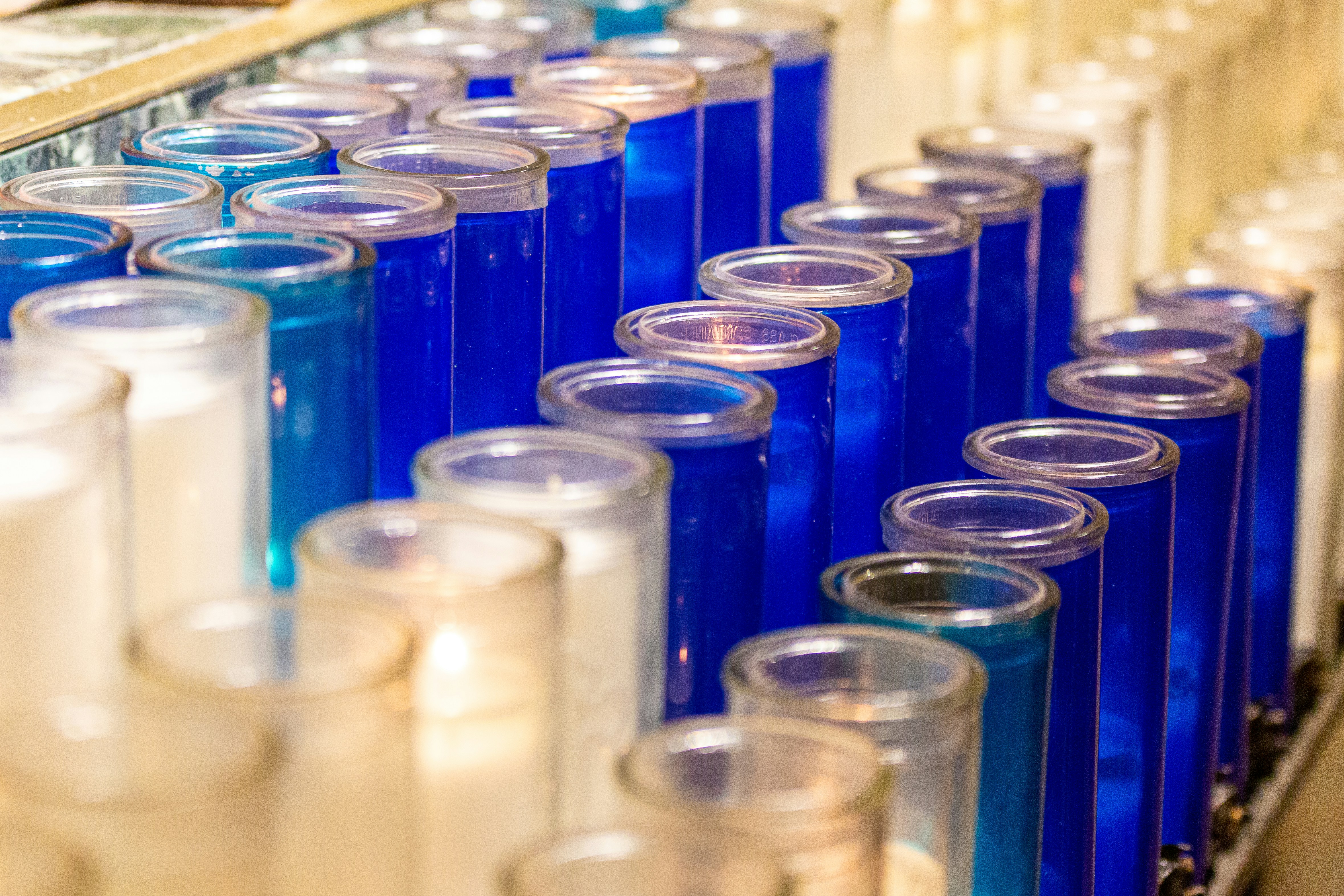 a row of blue and clear glass containers, Church candles