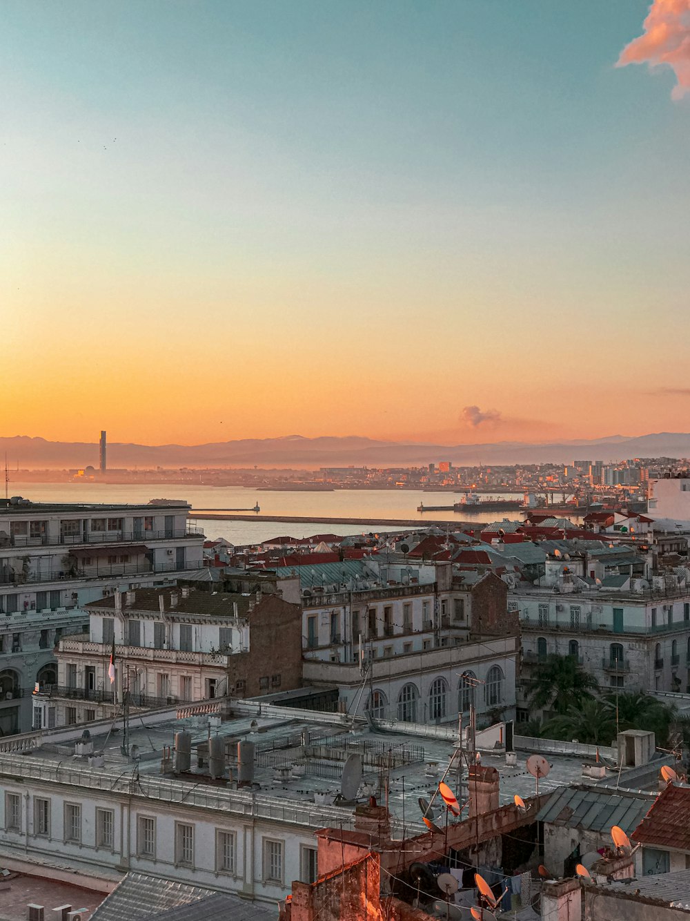 a view of a city at sunset with the ocean in the background