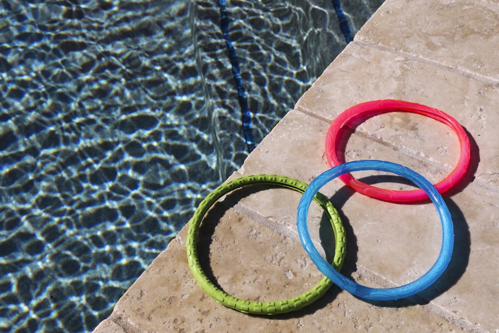 three rings sitting on the edge of a swimming pool