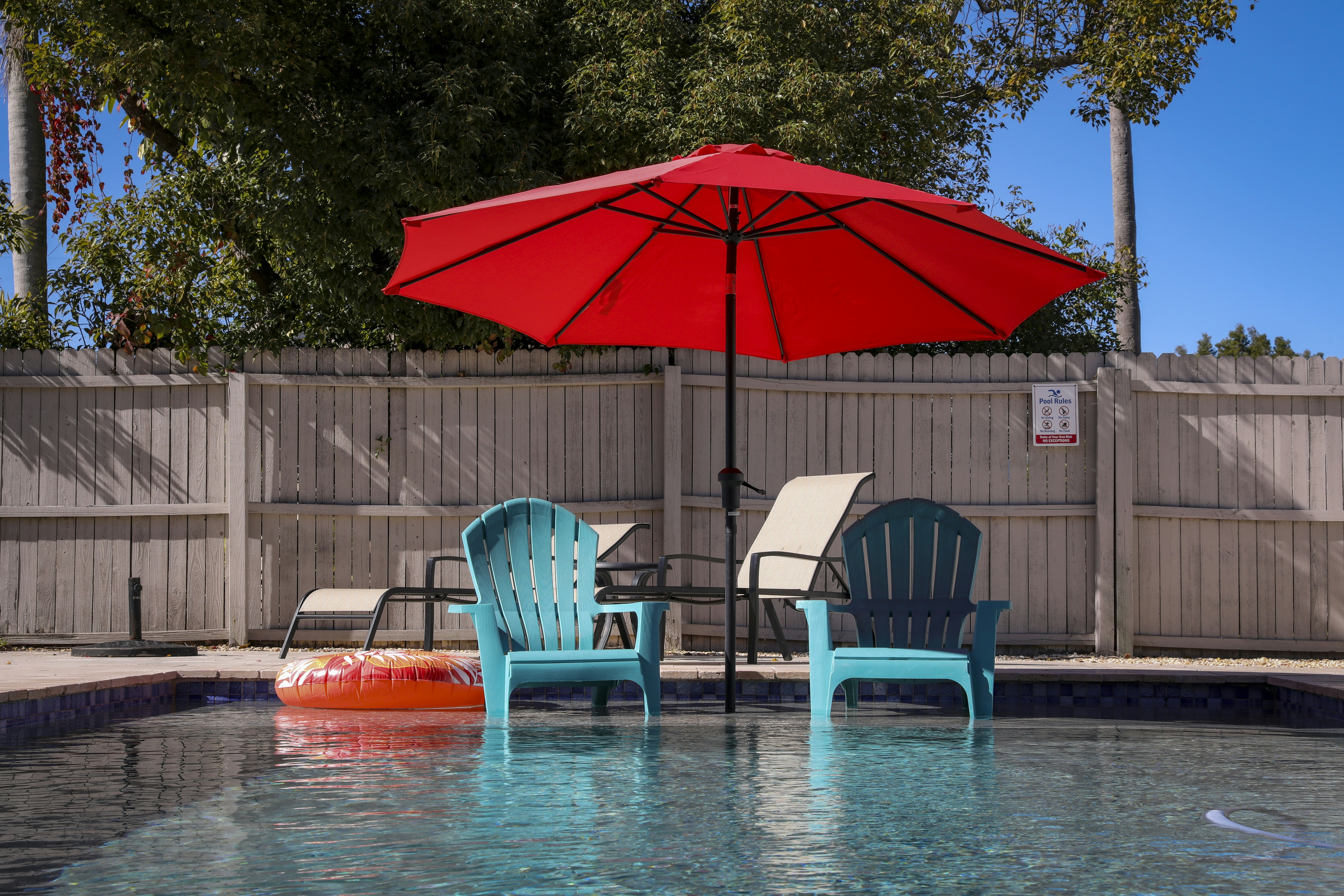 a pool with two chairs and an umbrella, backyard moments.