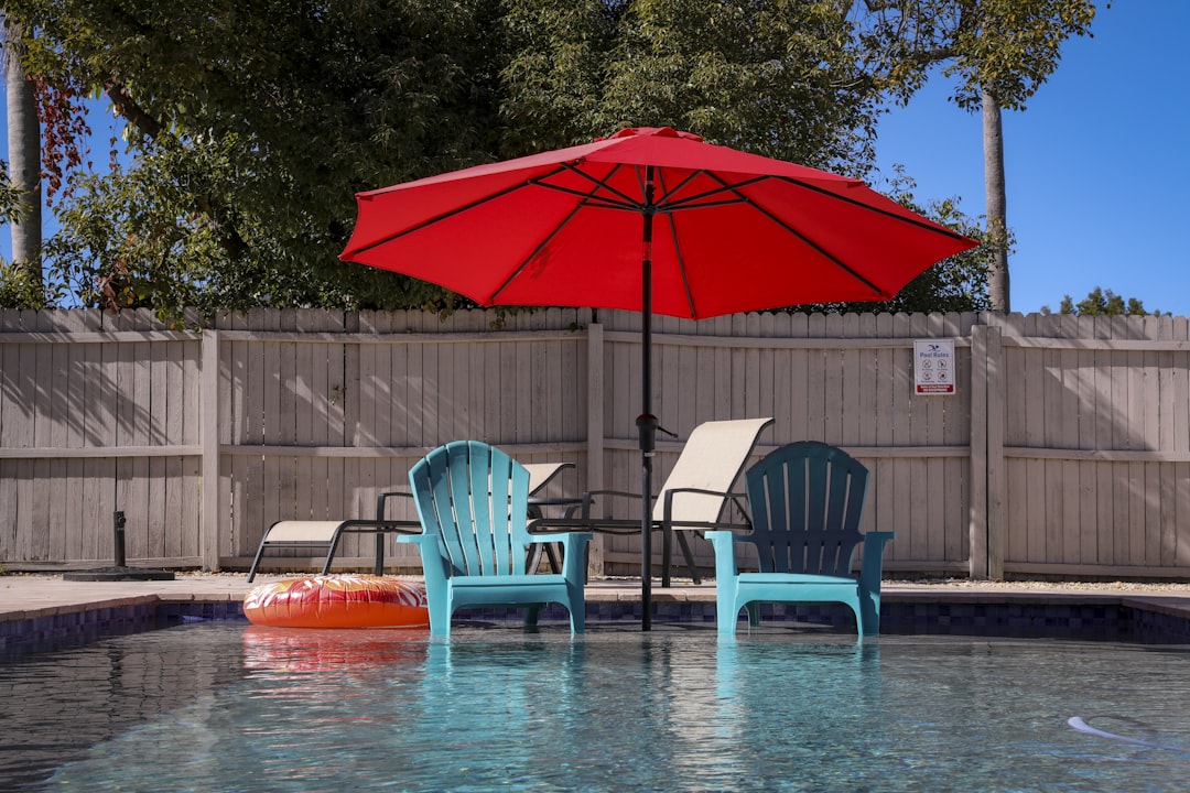 a pool with two chairs and an umbrella, backyard moments.