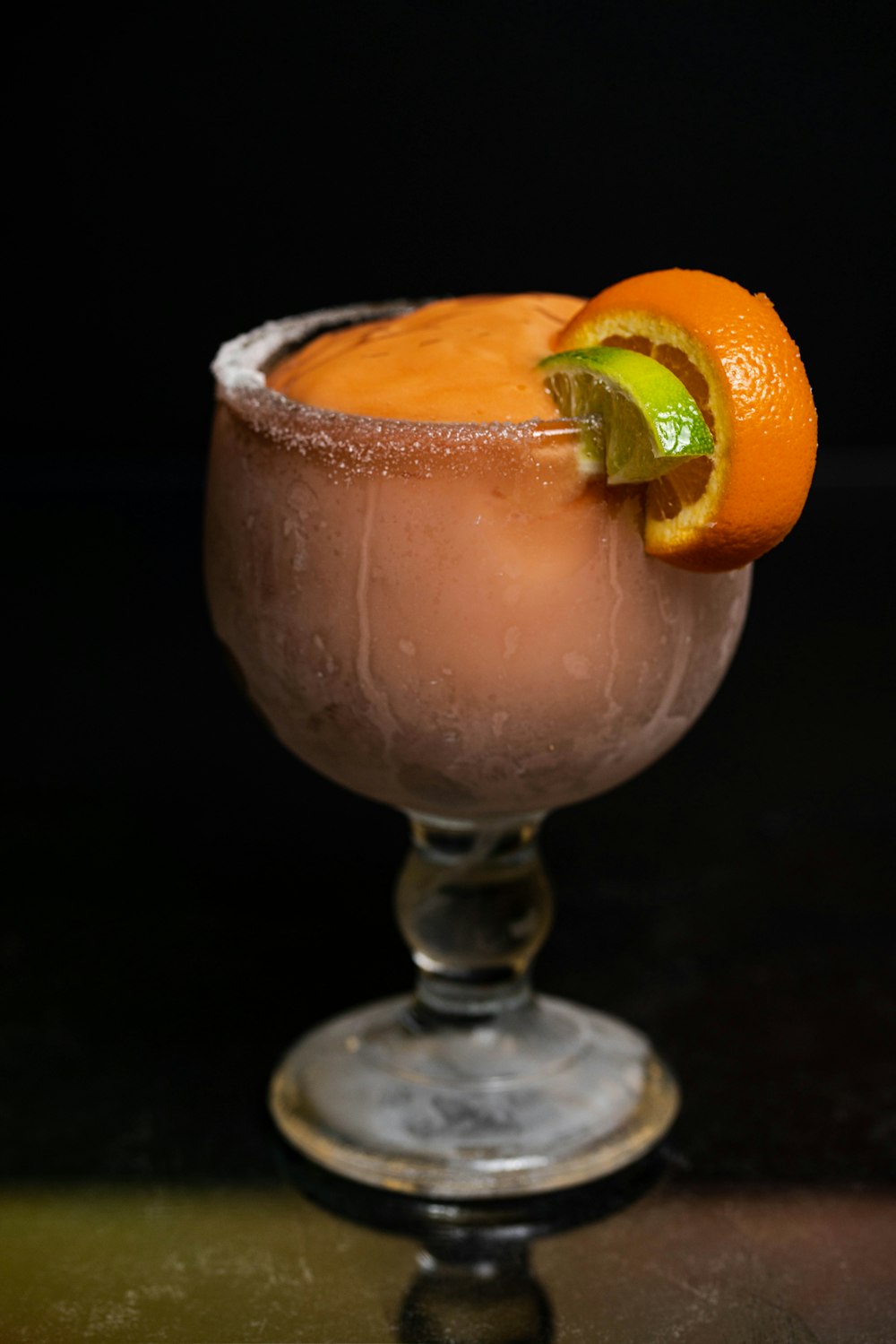 a glass filled with a drink and an orange slice on top of it