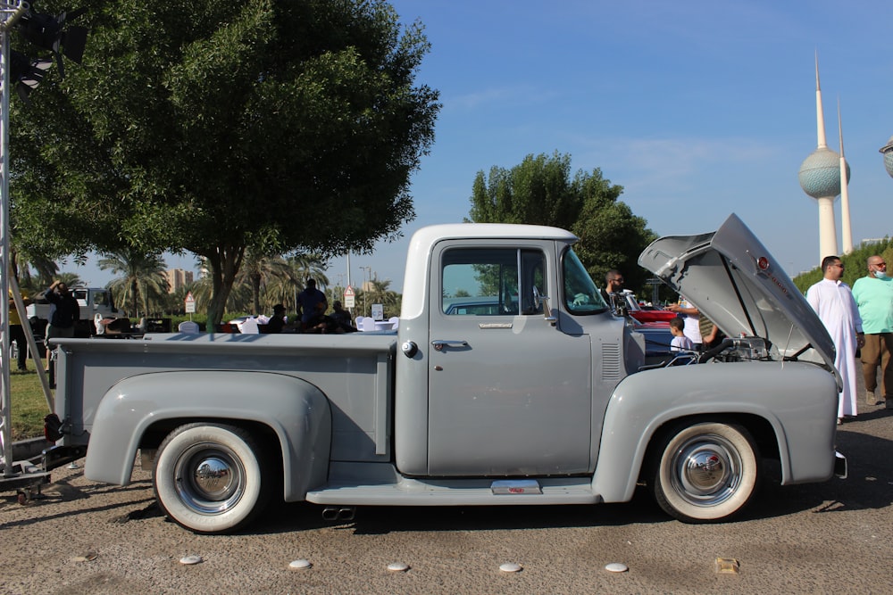 a gray truck parked on a street next to a crowd of people