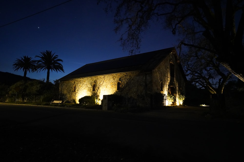 a church lit up at night with palm trees