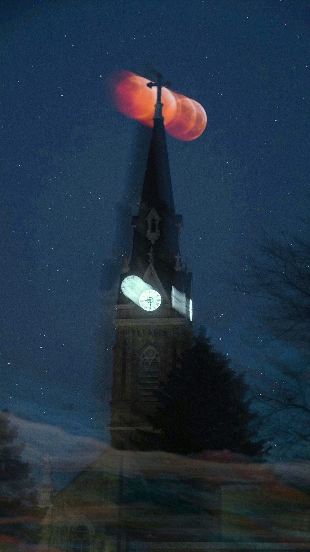 a clock tower with a red moon in the sky