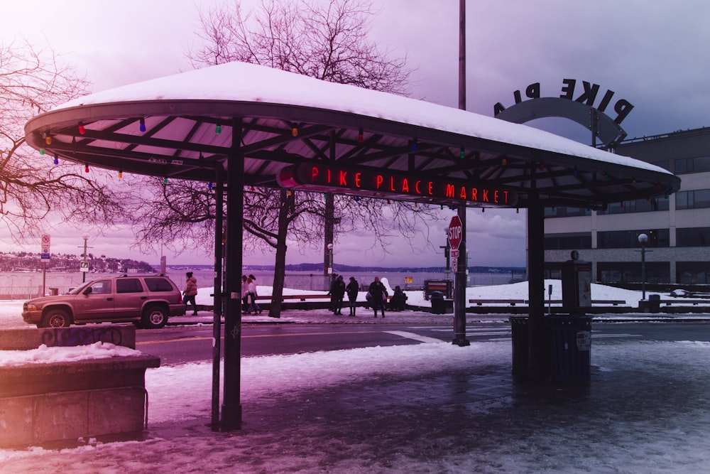 a bus stop covered in snow next to a building