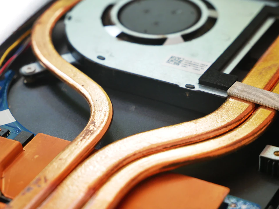 The image shows a close-up view of an internal computer fan, with its blades visible and a copper-colored heat sink resting on top of it. The heat sink is positioned at the bottom right corner of the frame, while the fan's blades are located in the center left area.