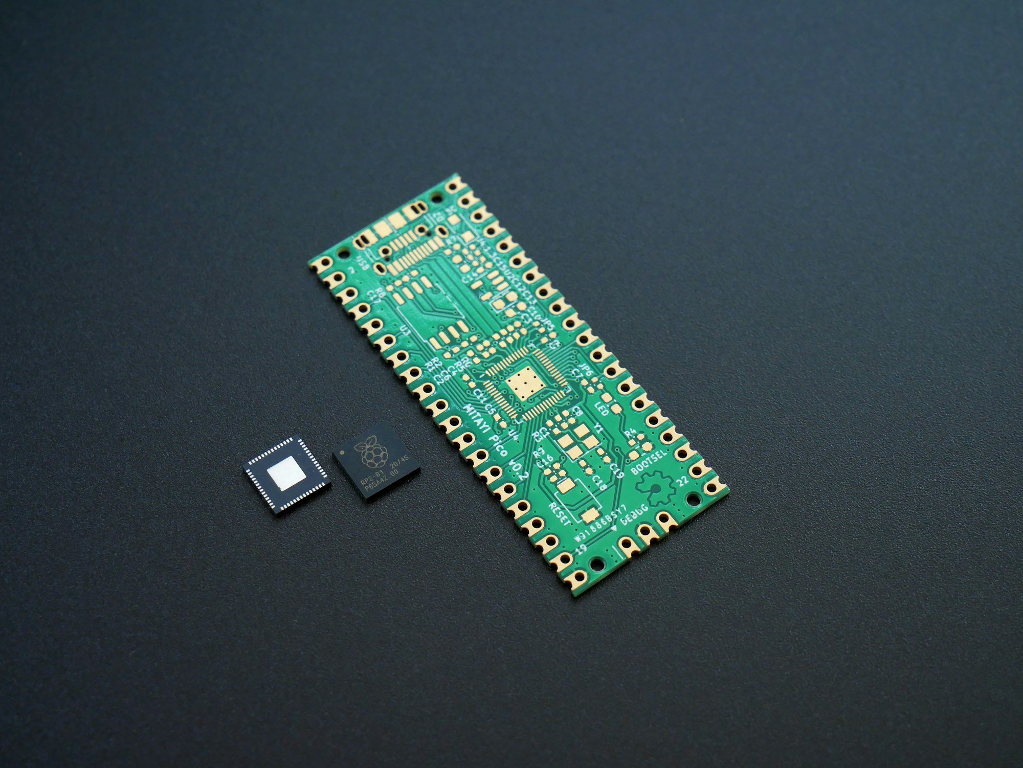 A plain Mitayi Pico RP2040 PCB near to two RP2040 microcontrollers.