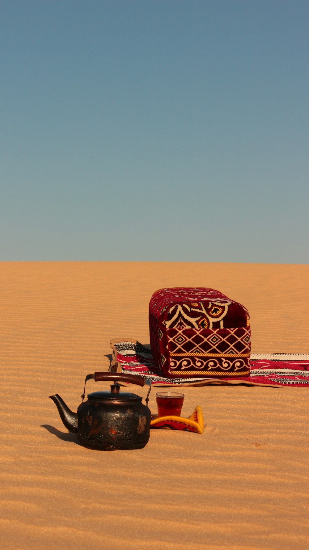 a tea pot and a rug in the desert