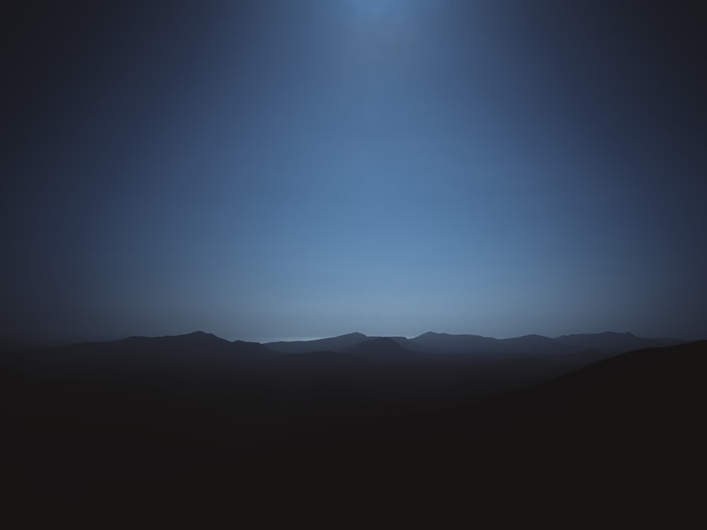 une vue d’une chaîne de montagnes la nuit avec la lune dans le ciel