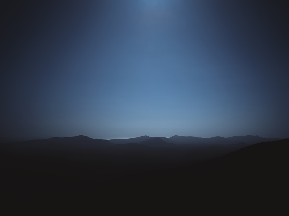 a view of a mountain range at night with the moon in the sky