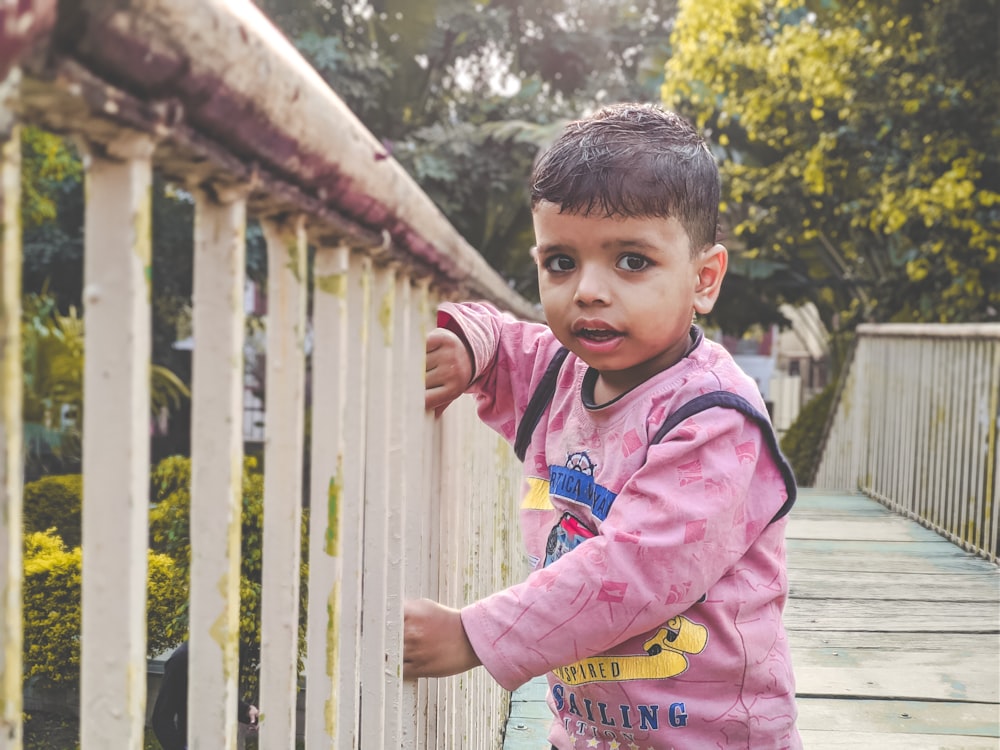 a little boy standing on a wooden bridge