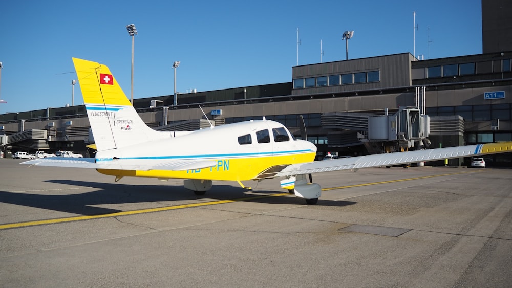 a small yellow and white plane parked in front of a building