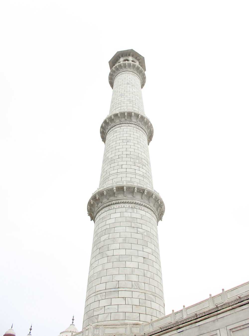 a tall white brick tower with a clock on it's side