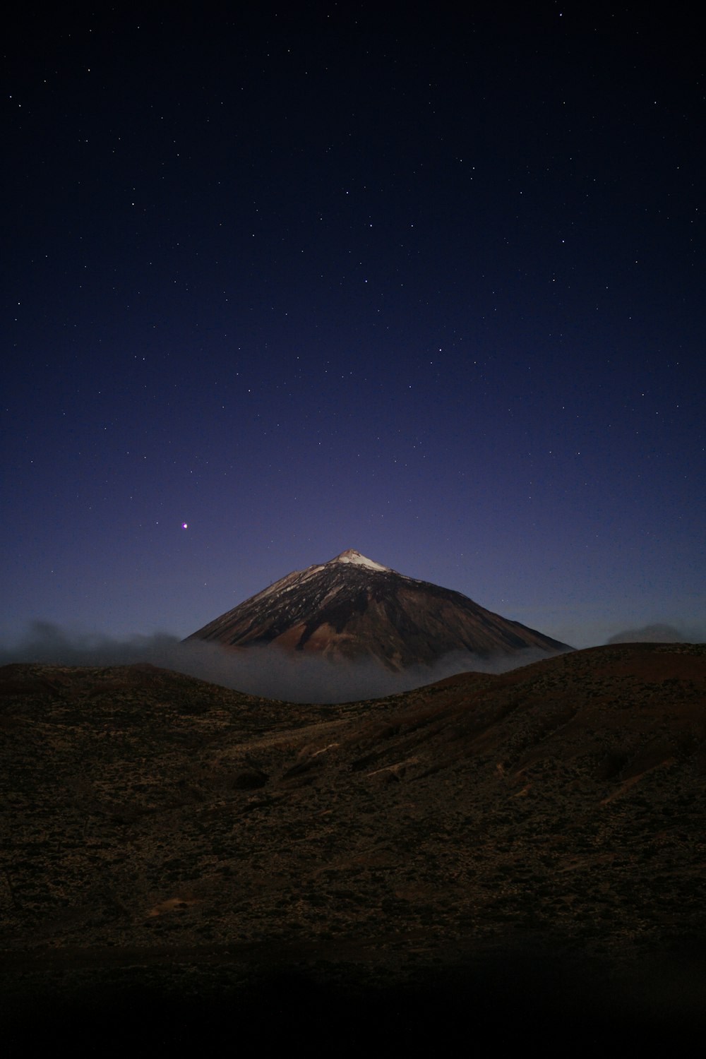 a mountain covered in fog and stars at night