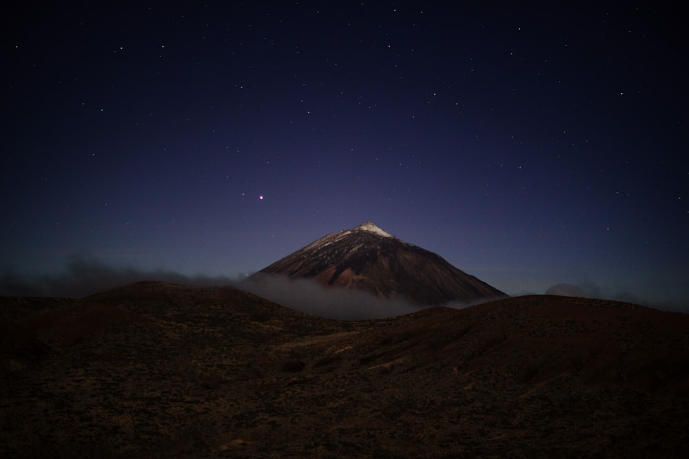 a mountain covered in fog under a night sky