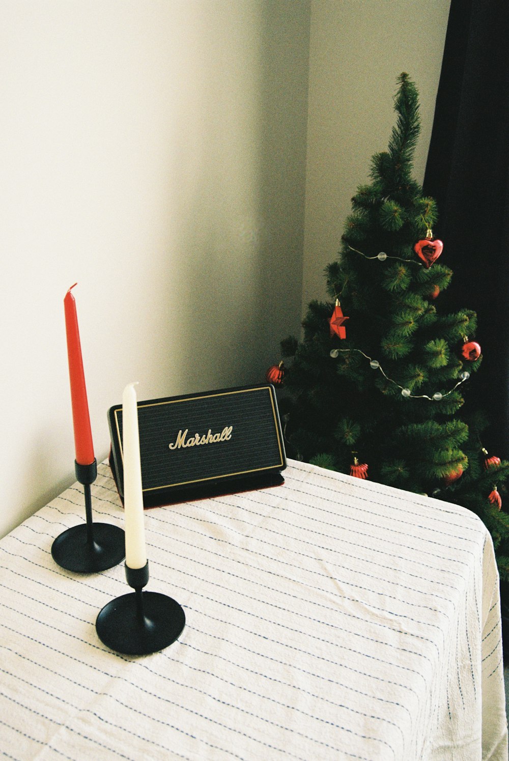 Zwei Kerzen auf einem Tisch mit einem Weihnachtsbaum im Hintergrund