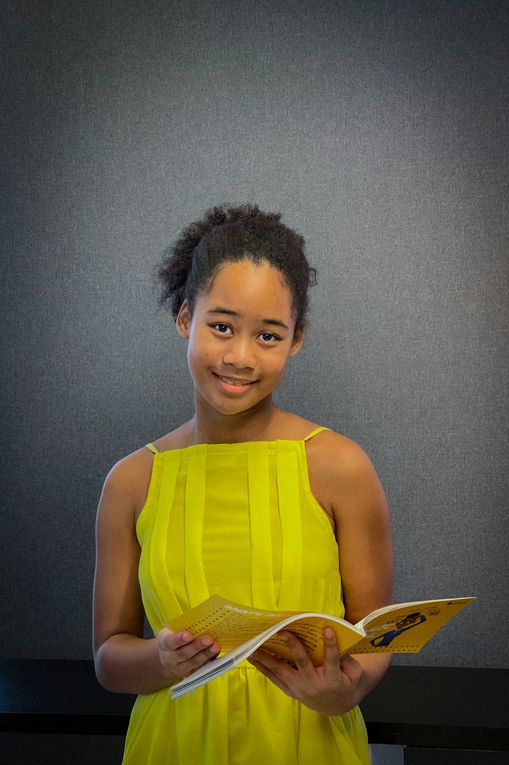 Una mujer con un vestido amarillo sosteniendo un libro