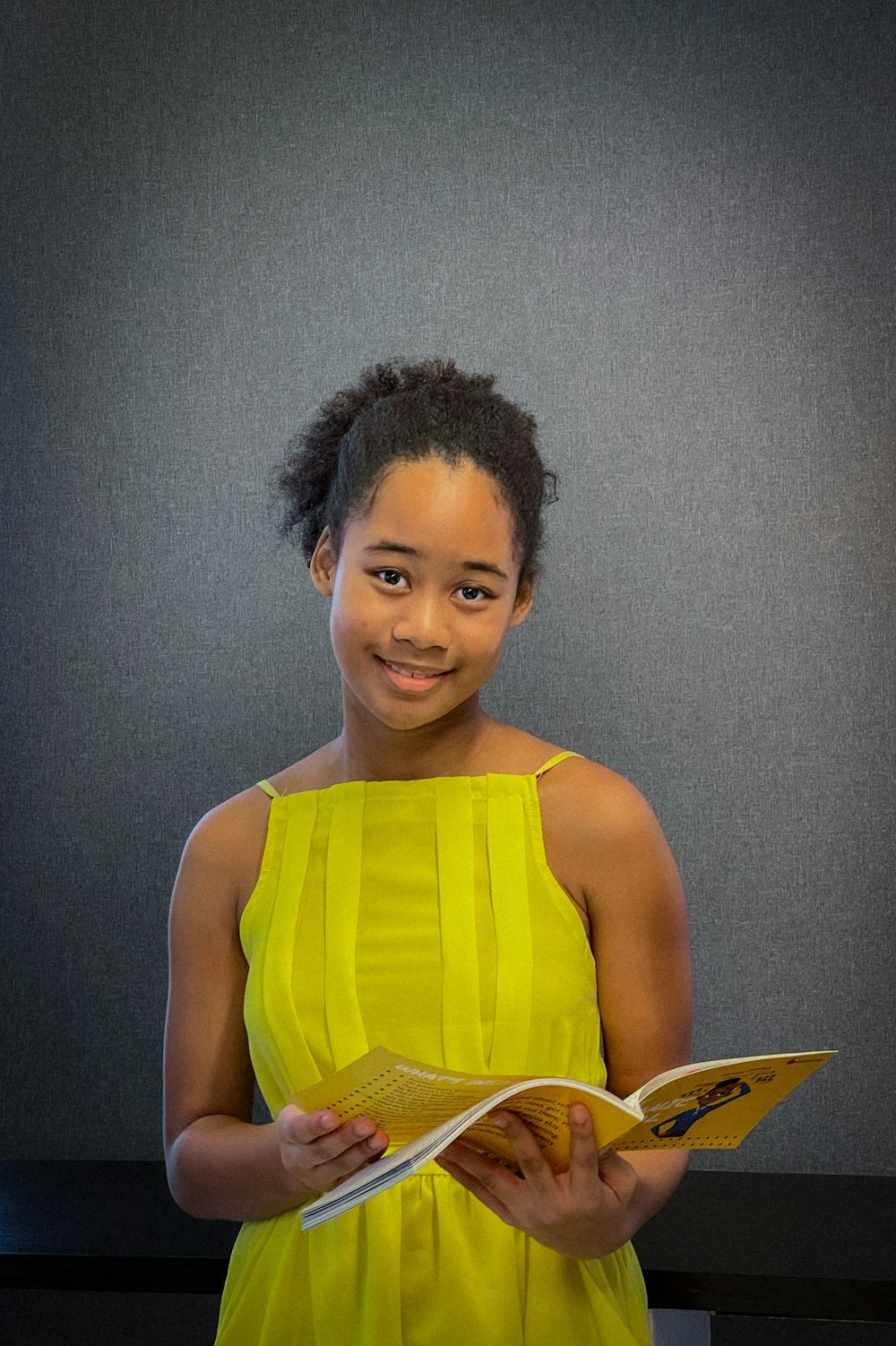 a woman in a yellow dress holding a book