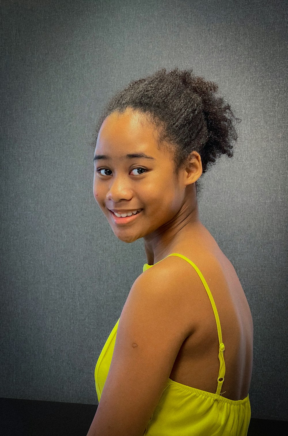 a woman in a yellow dress smiling at the camera