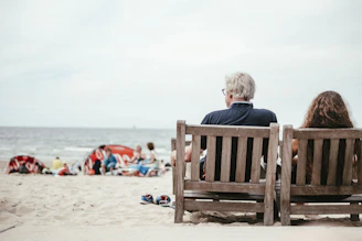 a couple of people sitting on top of a wooden bench