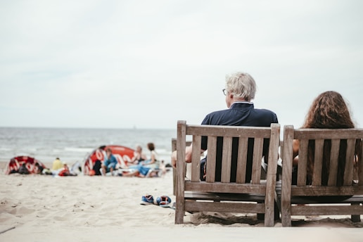 a couple of people sitting on top of a wooden bench