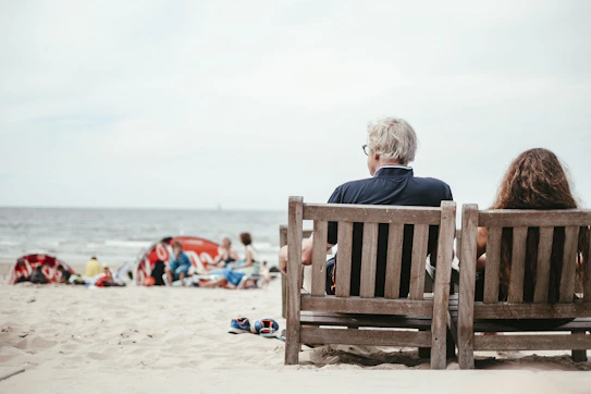 a couple of people sitting on top of a wooden bench