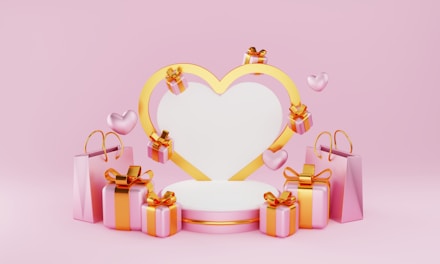 A heart-shaped frame with a gold outline is surrounded by floating pink hearts and several gift boxes wrapped with pink paper and gold ribbons. Pink shopping bags are placed on both sides, creating a celebratory and romantic atmosphere against a pink background.