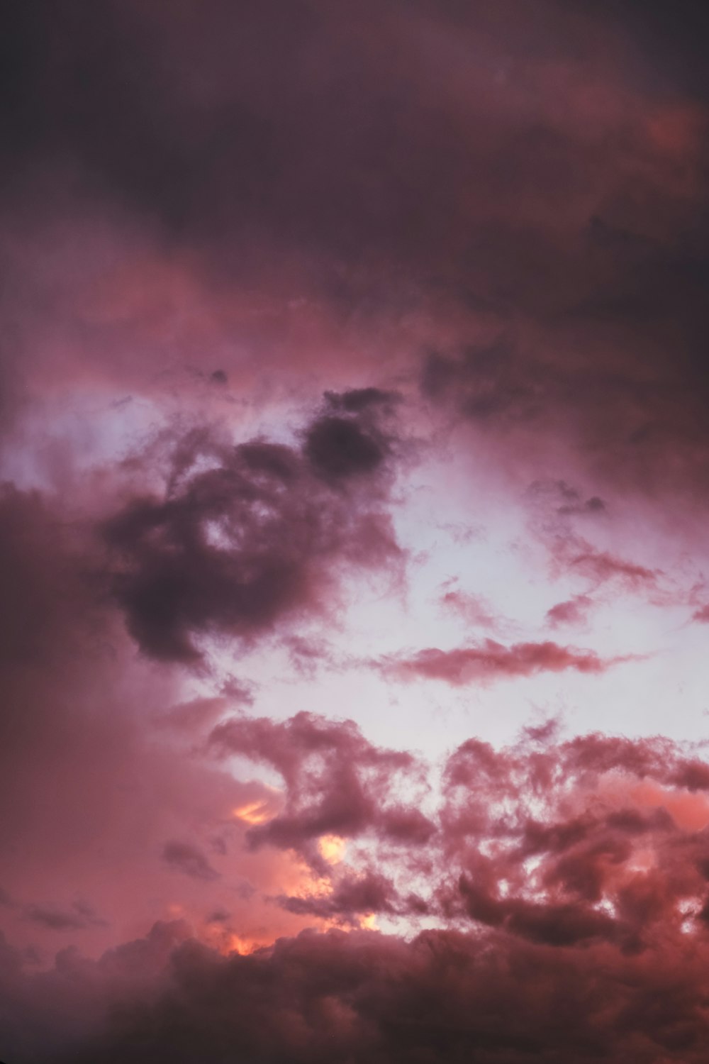 a plane flying through a cloudy sky at sunset