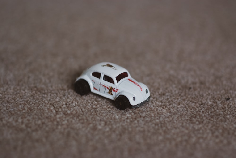 a white toy car sitting on top of a carpet