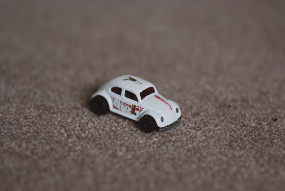 una macchinina giocattolo bianca seduta sopra un tappeto