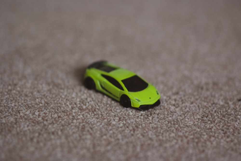 Una macchina giocattolo verde seduta sopra un tappeto