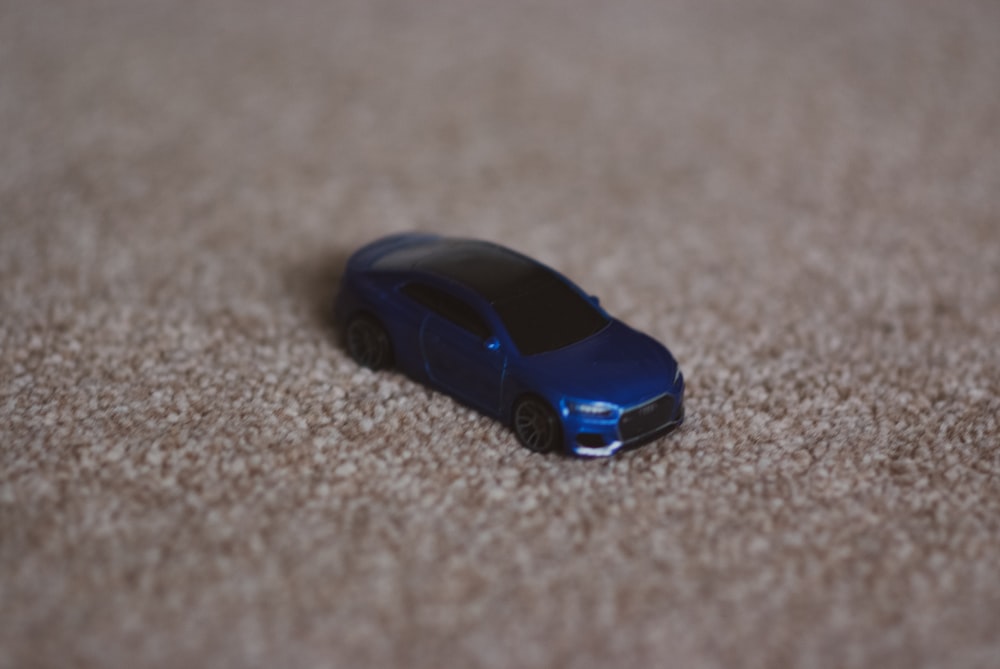 Un coche de juguete sentado en un suelo alfombrado