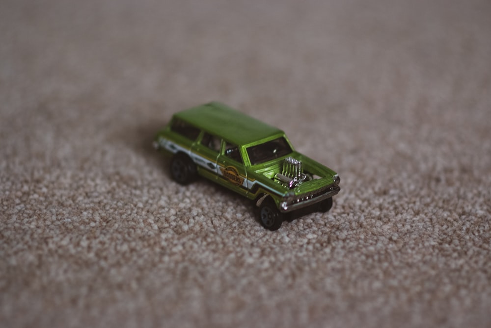 Ein grüner Spielzeuglastwagen, der auf einem Teppich sitzt