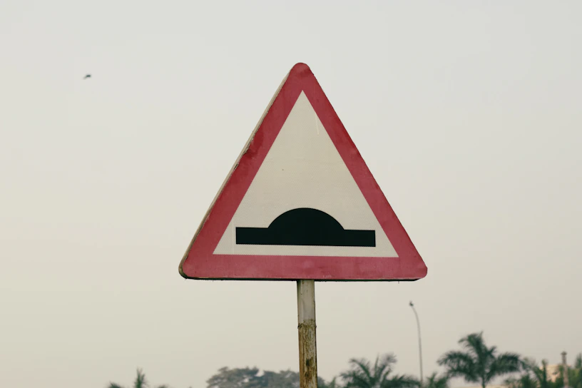 a red and white triangular sign on a pole