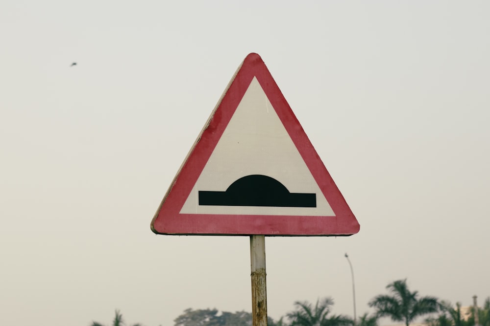 a red and white triangular sign on a pole