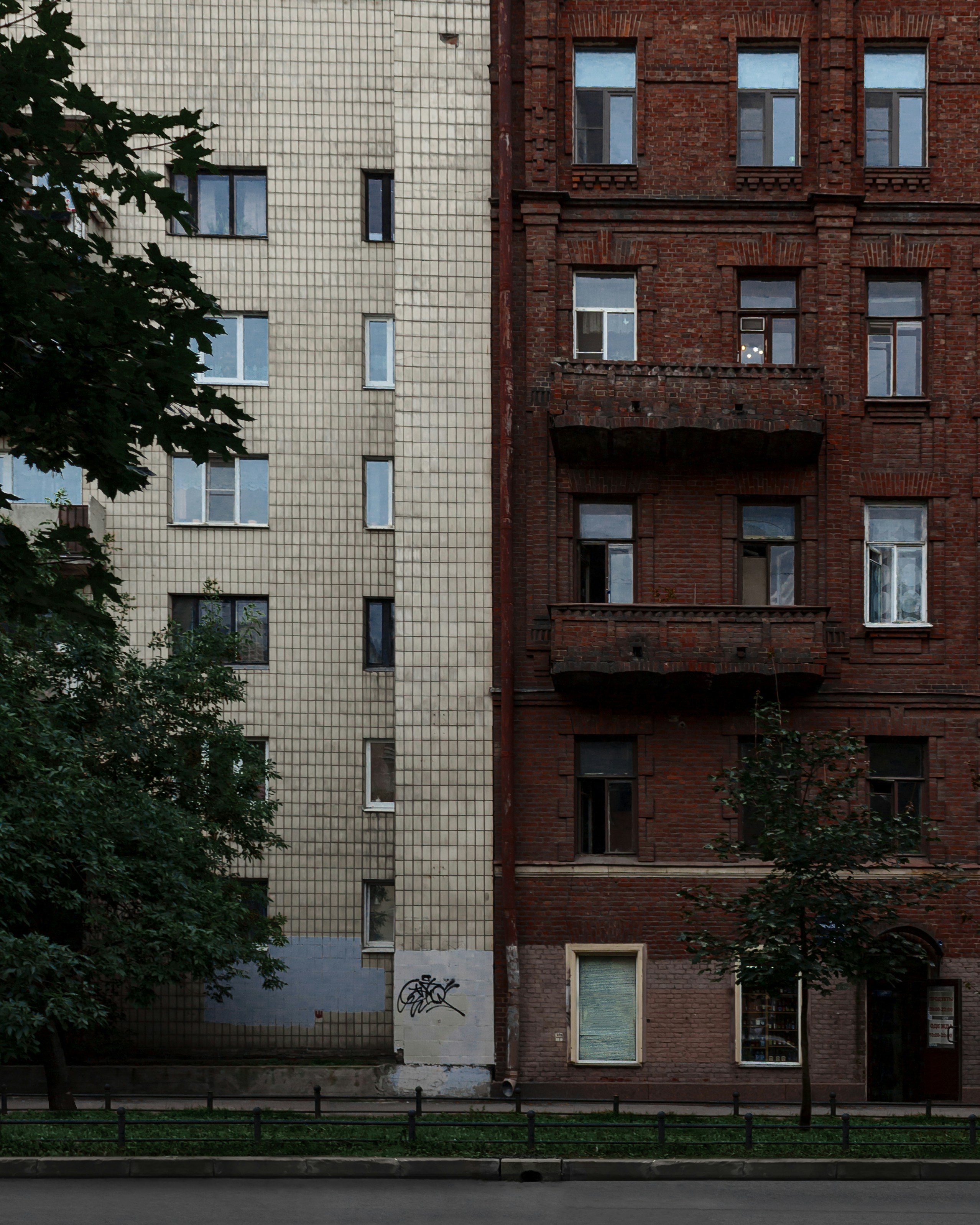 a tall brick building sitting next to a lush green tree