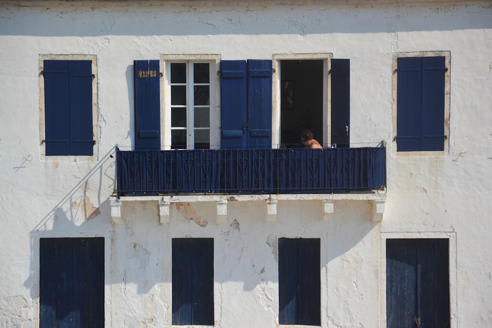 a white building with blue shutters and a balcony