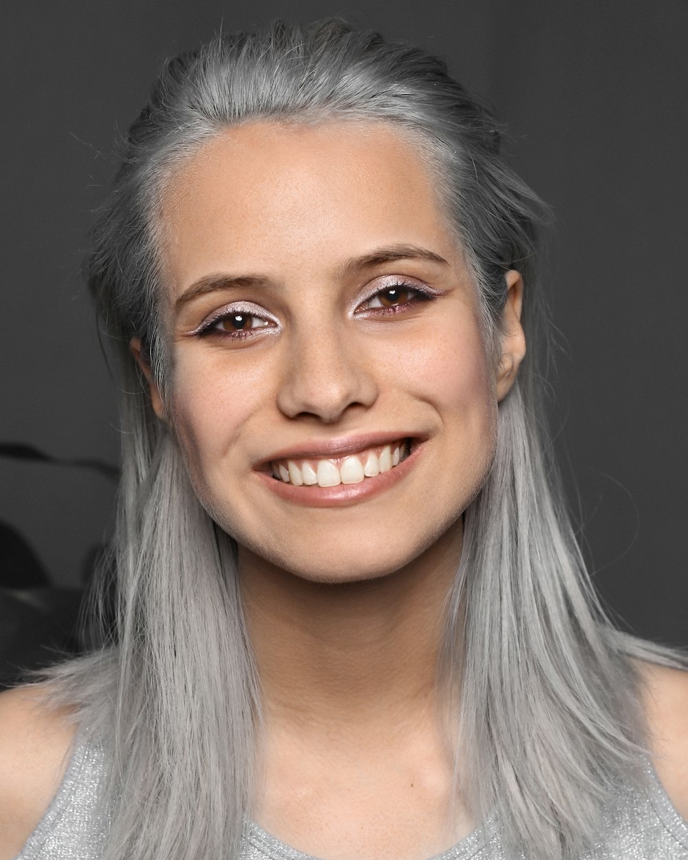 Una donna con i capelli grigi che sorride alla macchina fotografica
