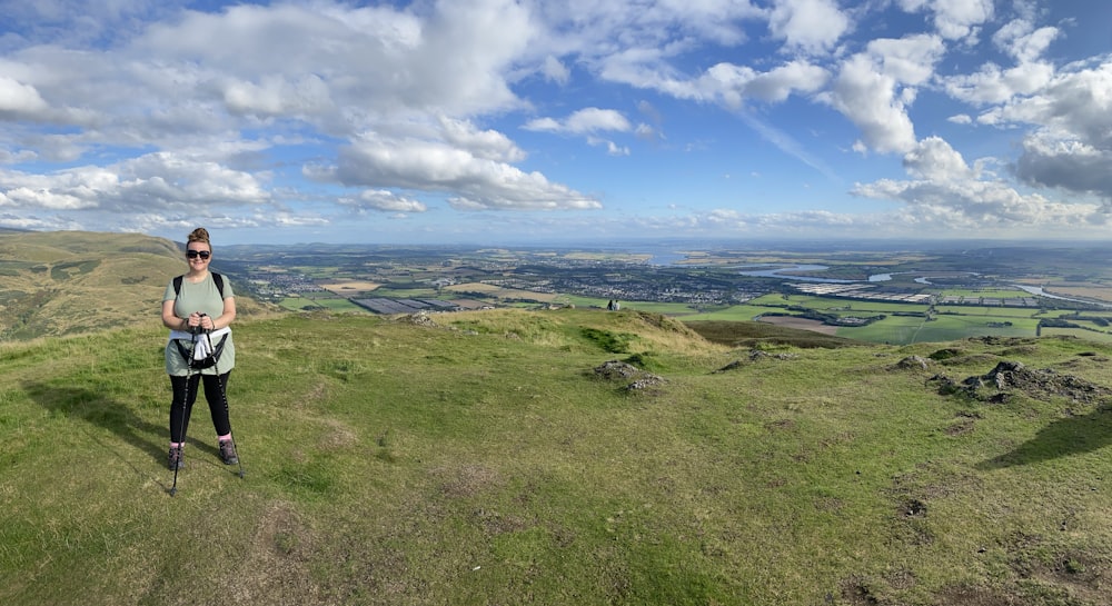 a woman standing on top of a lush green hillside