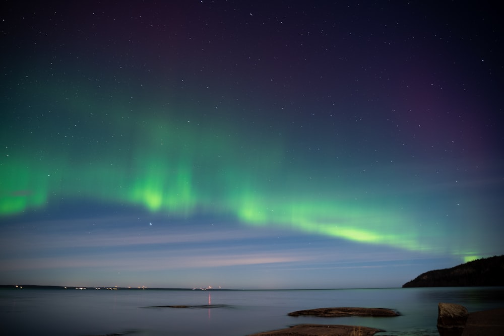 a green and purple aurora over a body of water